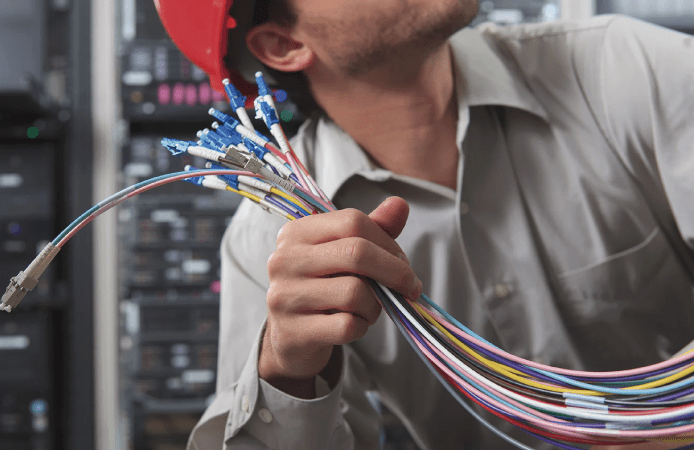 Imagen que representa un cable de fibra óptica multimodo sostenido por un ingeniero de Total Redes en proceso de configurar e implementar una instalación de fibra óptica.