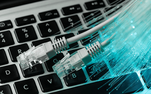 Fotografía donde se muestra la fibra óptica que es instalada por Total redes en conjunto con cables ethernet y un teclado de fondo.