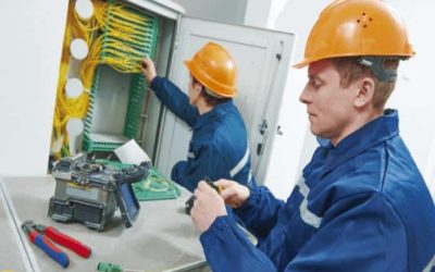 Imagen que muestra dos ingenieros de fibra óptica trabajando en una instalación de fibra óptica en un gabinete.