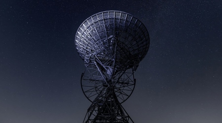 Fotografía que muestra una torre arriostrada apuntando a las estrellas en la noche.